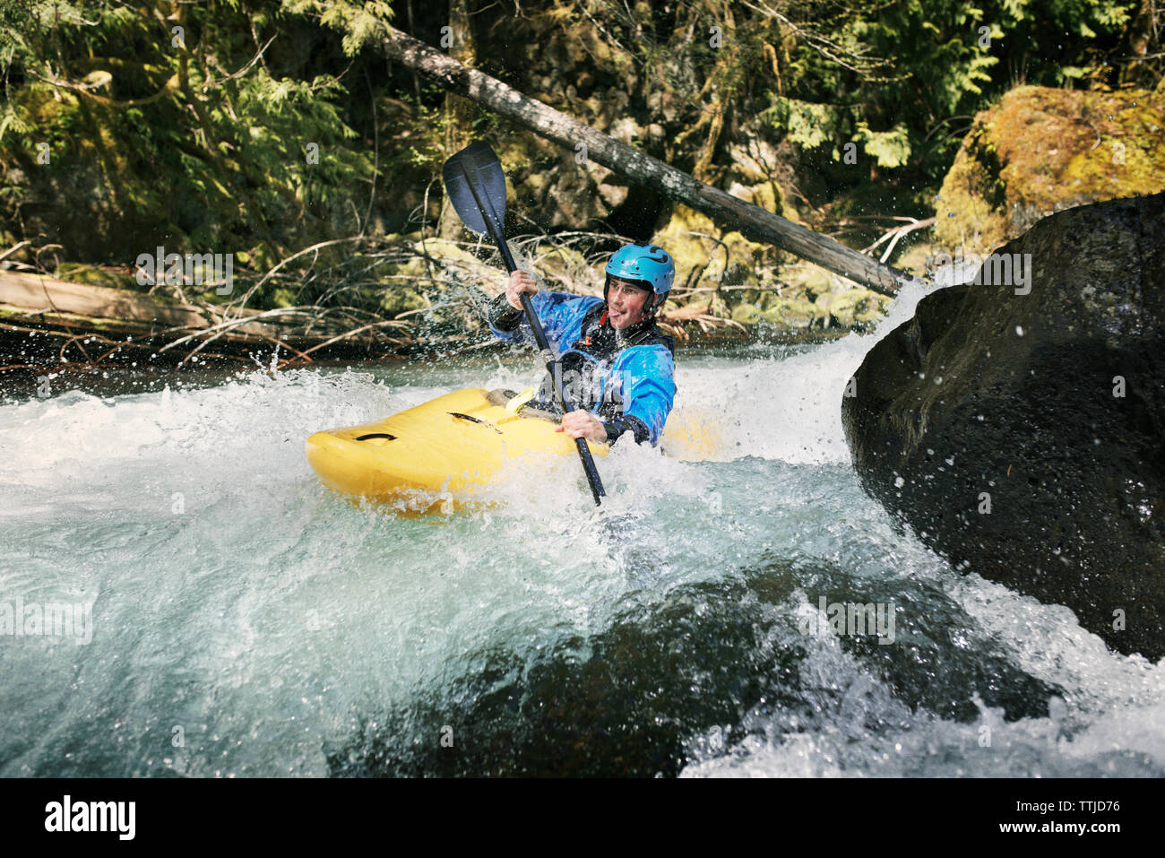 Man sticking out tongue while kayaking in river Stock Photo
