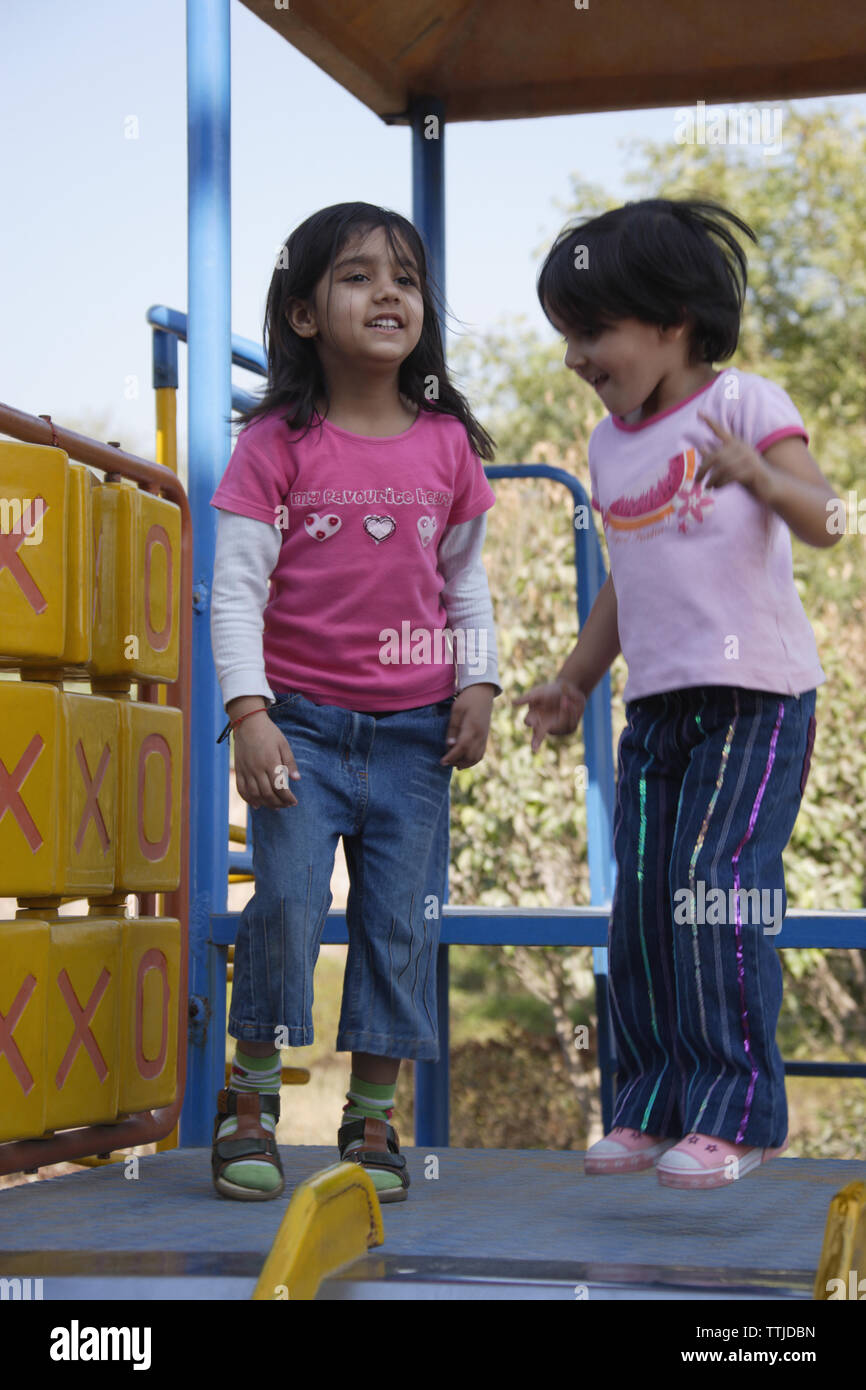 Two girls playing on slide in a playground Stock Photo - Alamy
