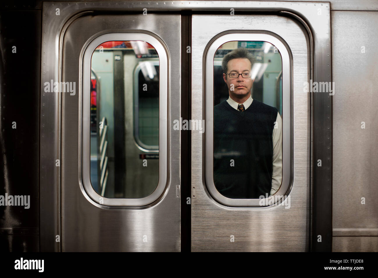 Businessman traveling in train seen through vehicle door Stock Photo