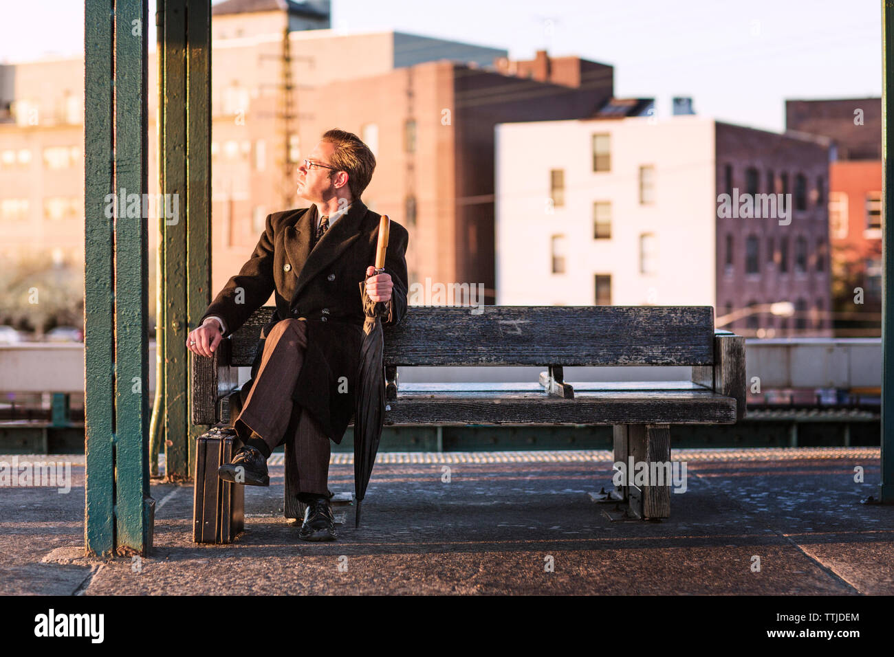 businessman looking away while sitting on bench at subway station Stock Photo