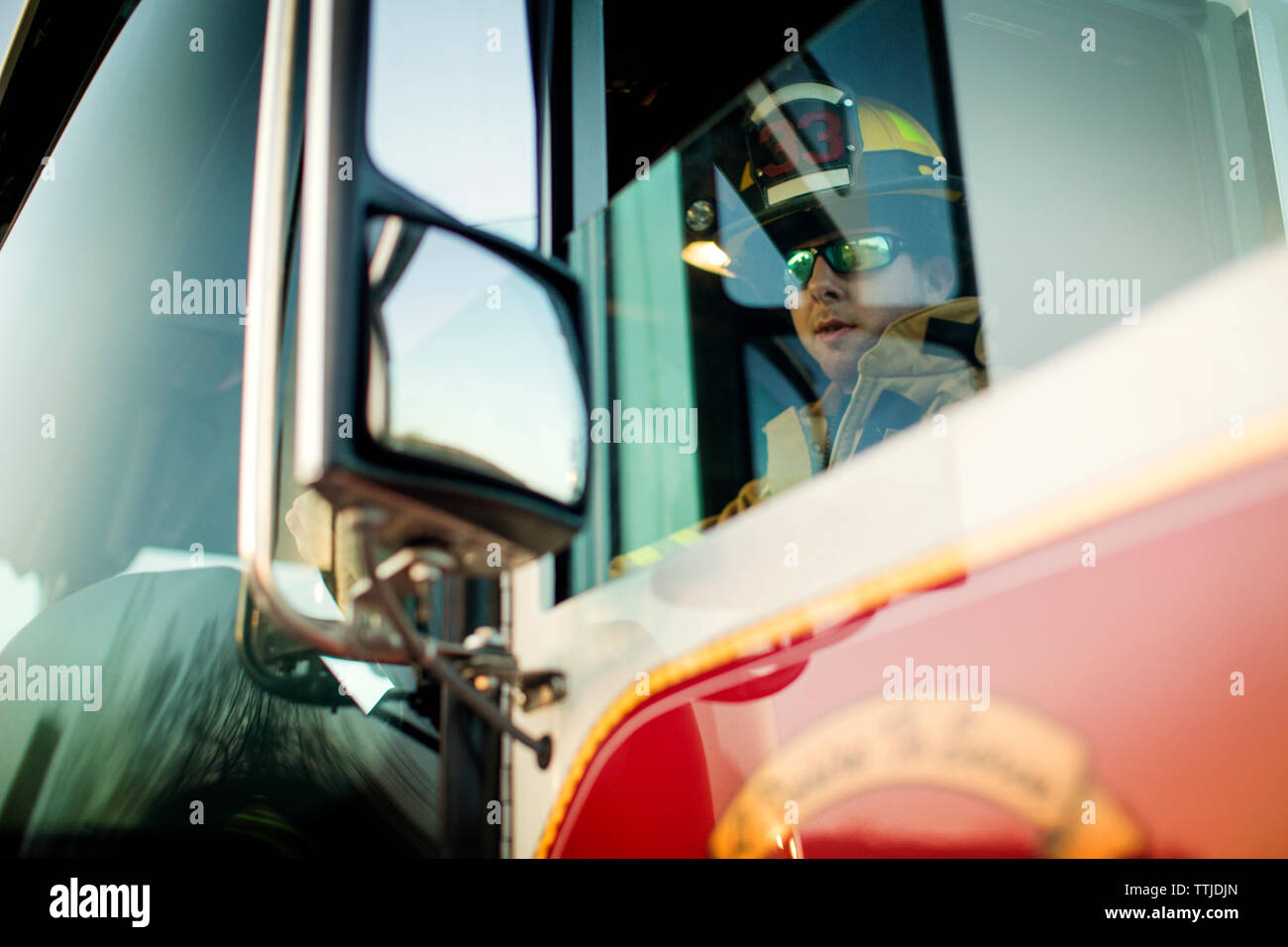 Confident firefighter sitting in fire engine Stock Photo