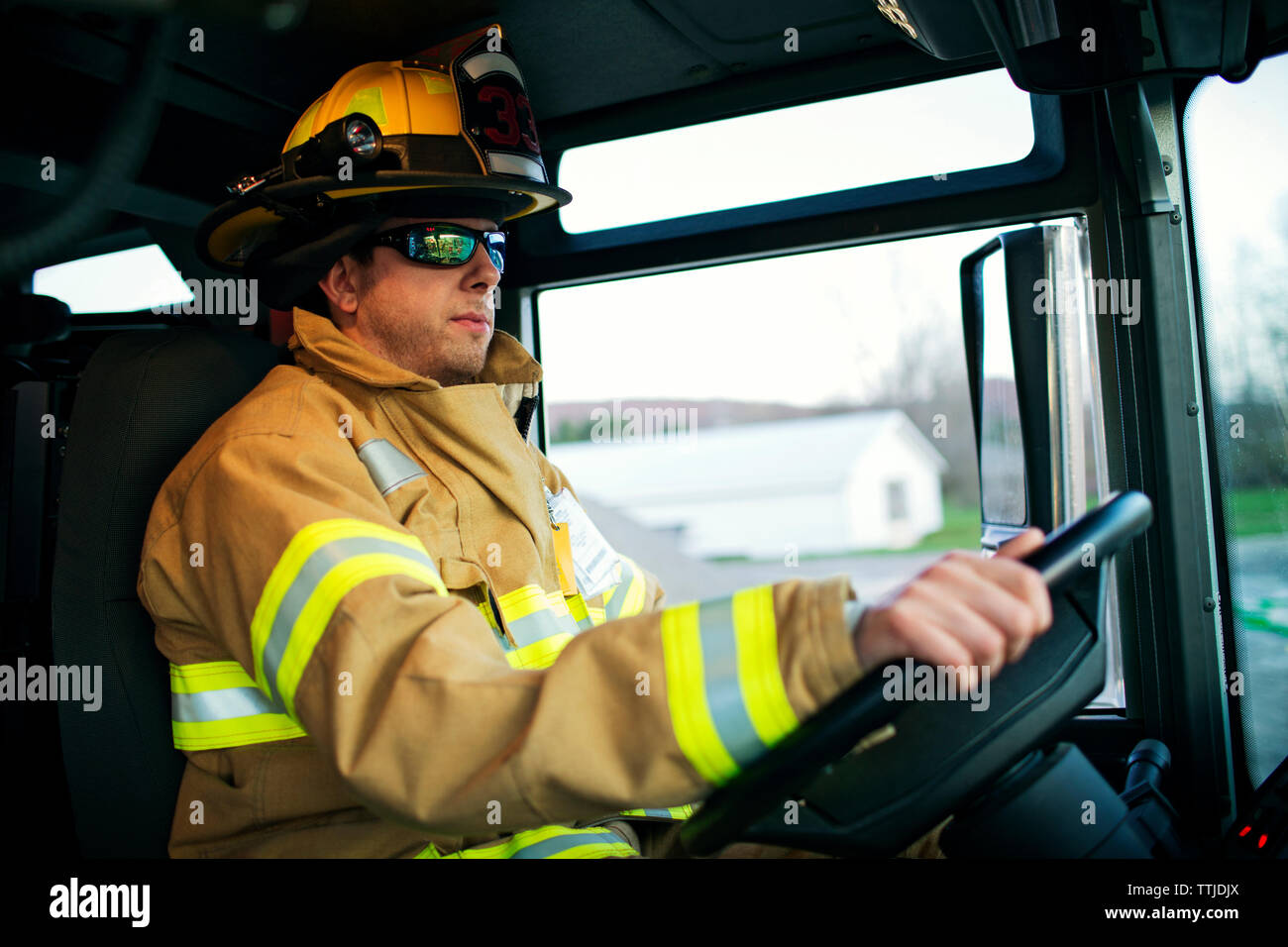 Confident firefighter driving fire engine Stock Photo