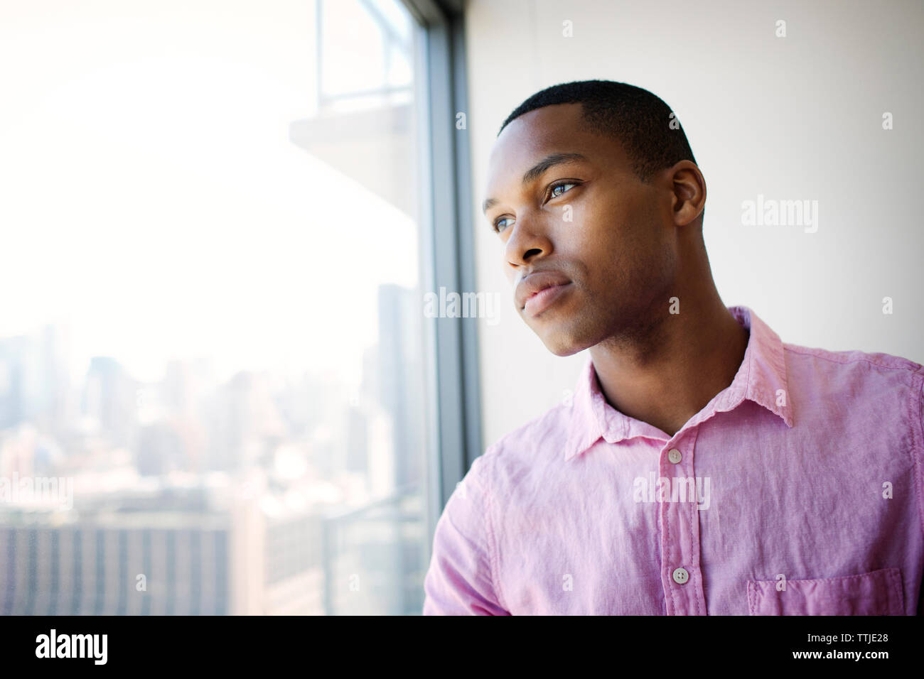 Thoughtful businessman looking through office window Stock Photo