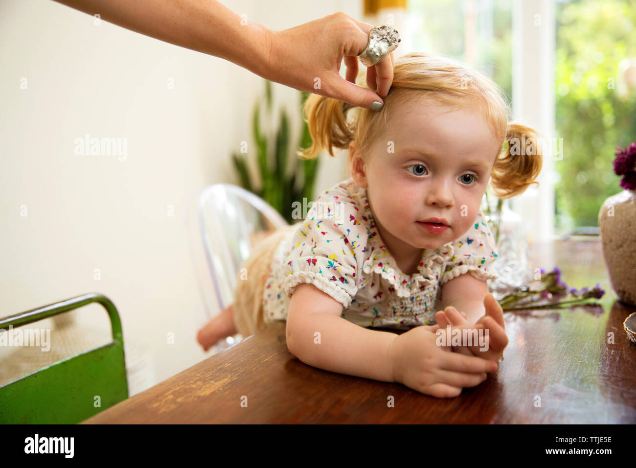 Cropped image of hand adjusting baby girl's hair at home Stock Photo