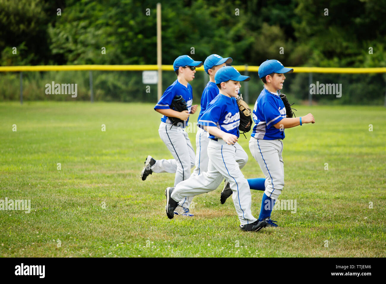 Baseball players running on grassy field Stock Photo