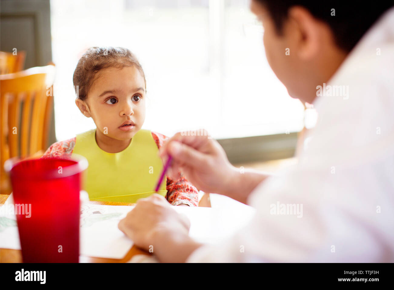 Girl looking at father while sitting at table in restaurant Stock Photo