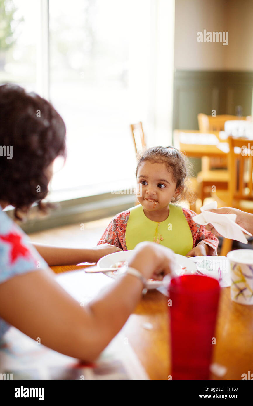 Girl looking at mother while sitting at table in restaurant Stock Photo