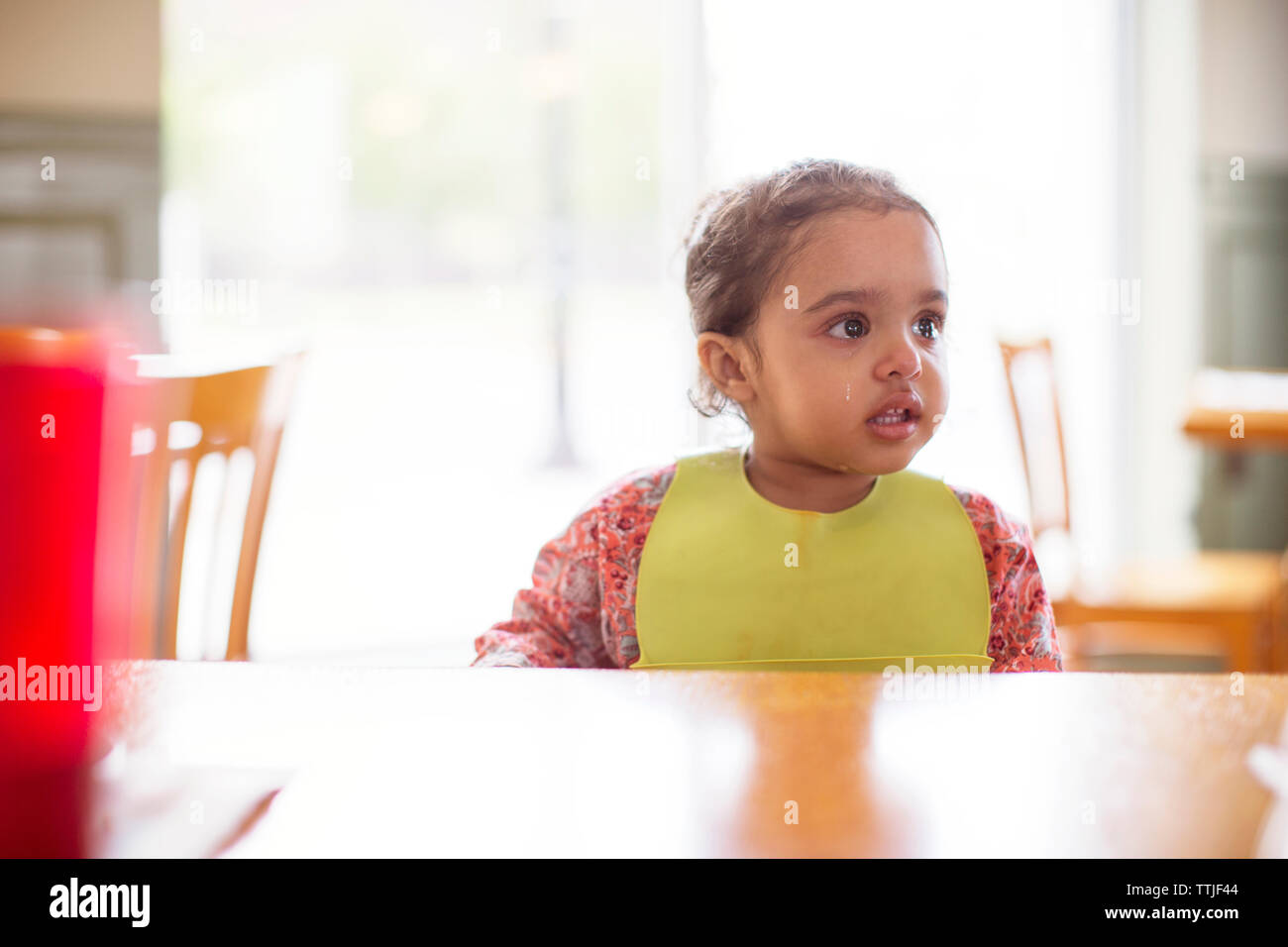 Girl crying while sitting at table in restaurant Stock Photo