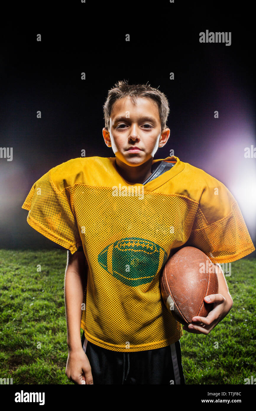 Portrait of American football player with ball standing on field Stock