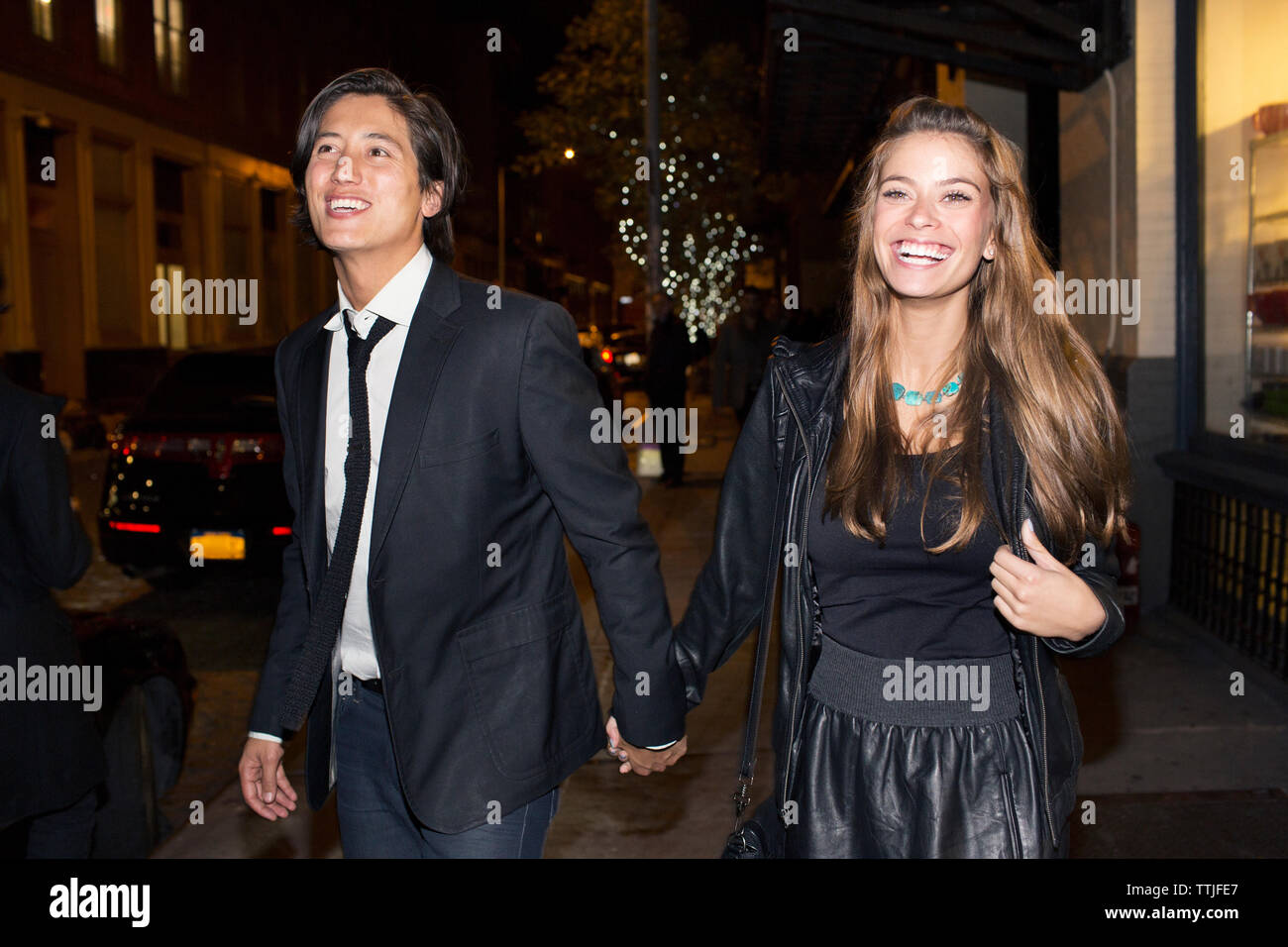 Happy couple holding hands and walking on street at night Stock Photo ...