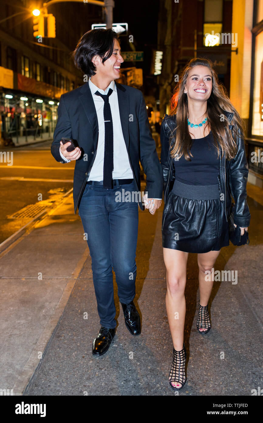 Happy couple holding hands and walking on city street Stock Photo - Alamy