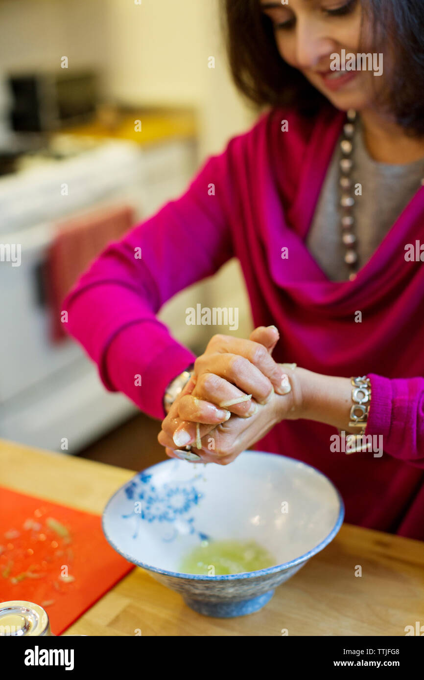 Woman pressing vegetables while preparing food at home Stock Photo