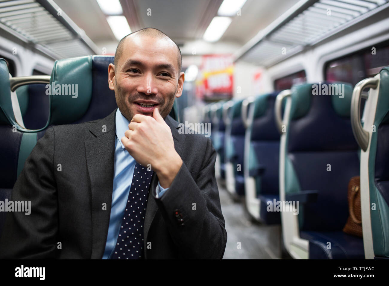 Happy businessman looking away while traveling in subway train Stock Photo