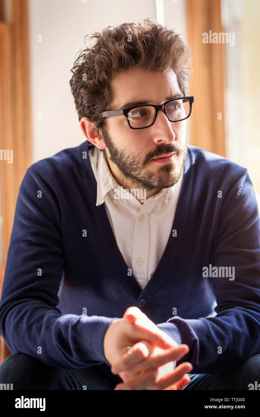 Thoughtful man looking away while sitting at home Stock Photo