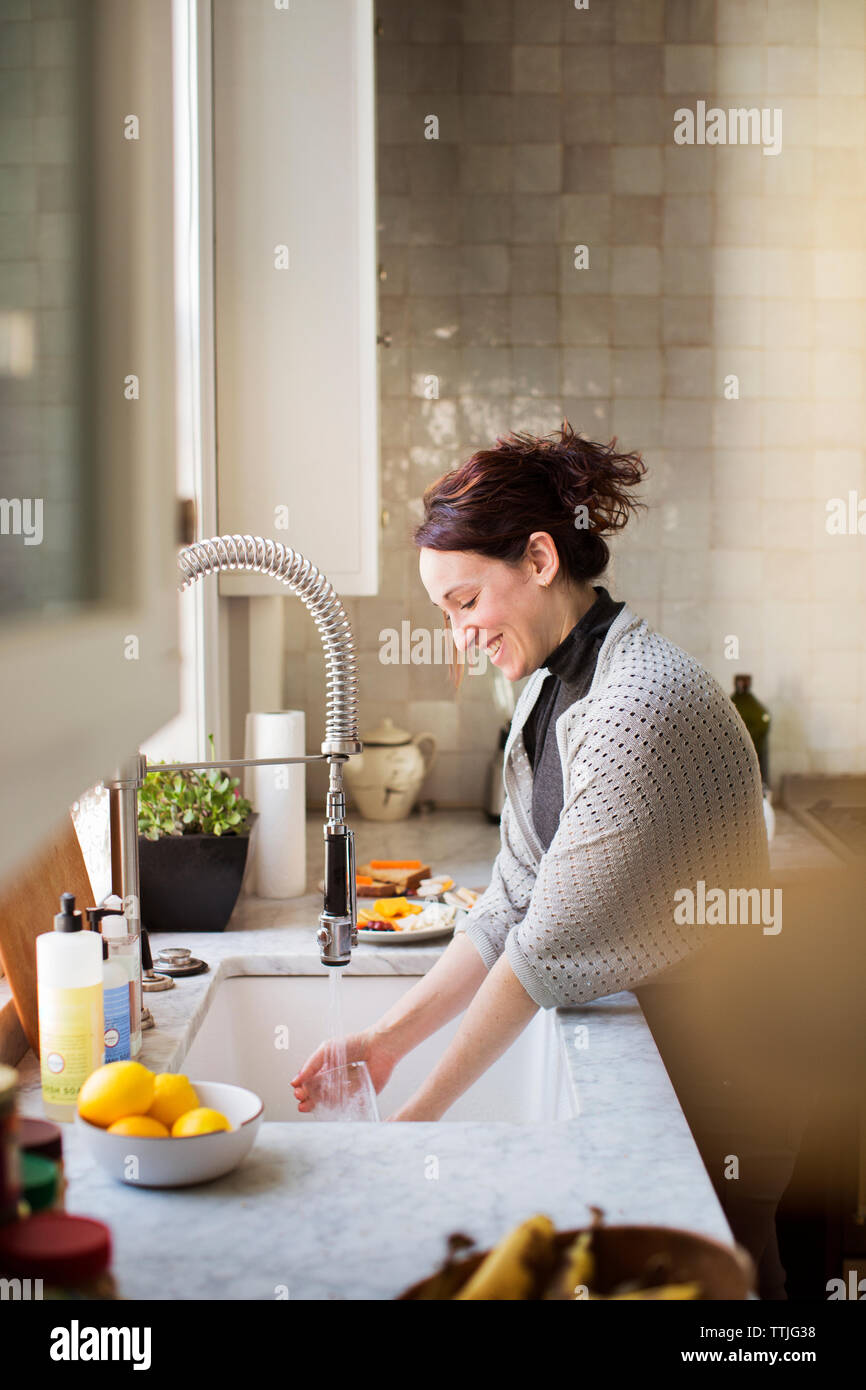Side view of woman washing utensils at home Stock Photo Alamy