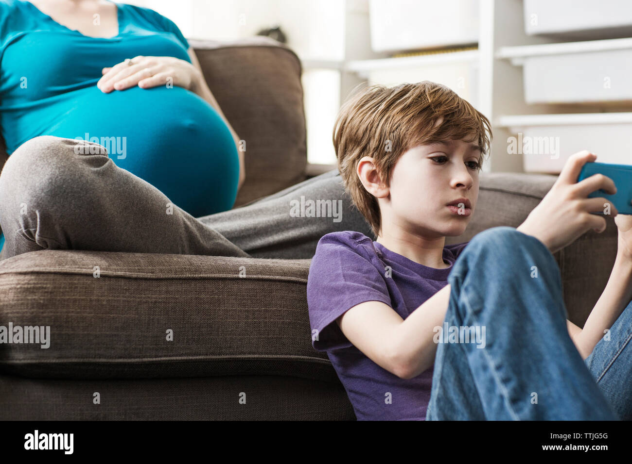 Boy using smart phone while sitting on floor at home Stock Photo