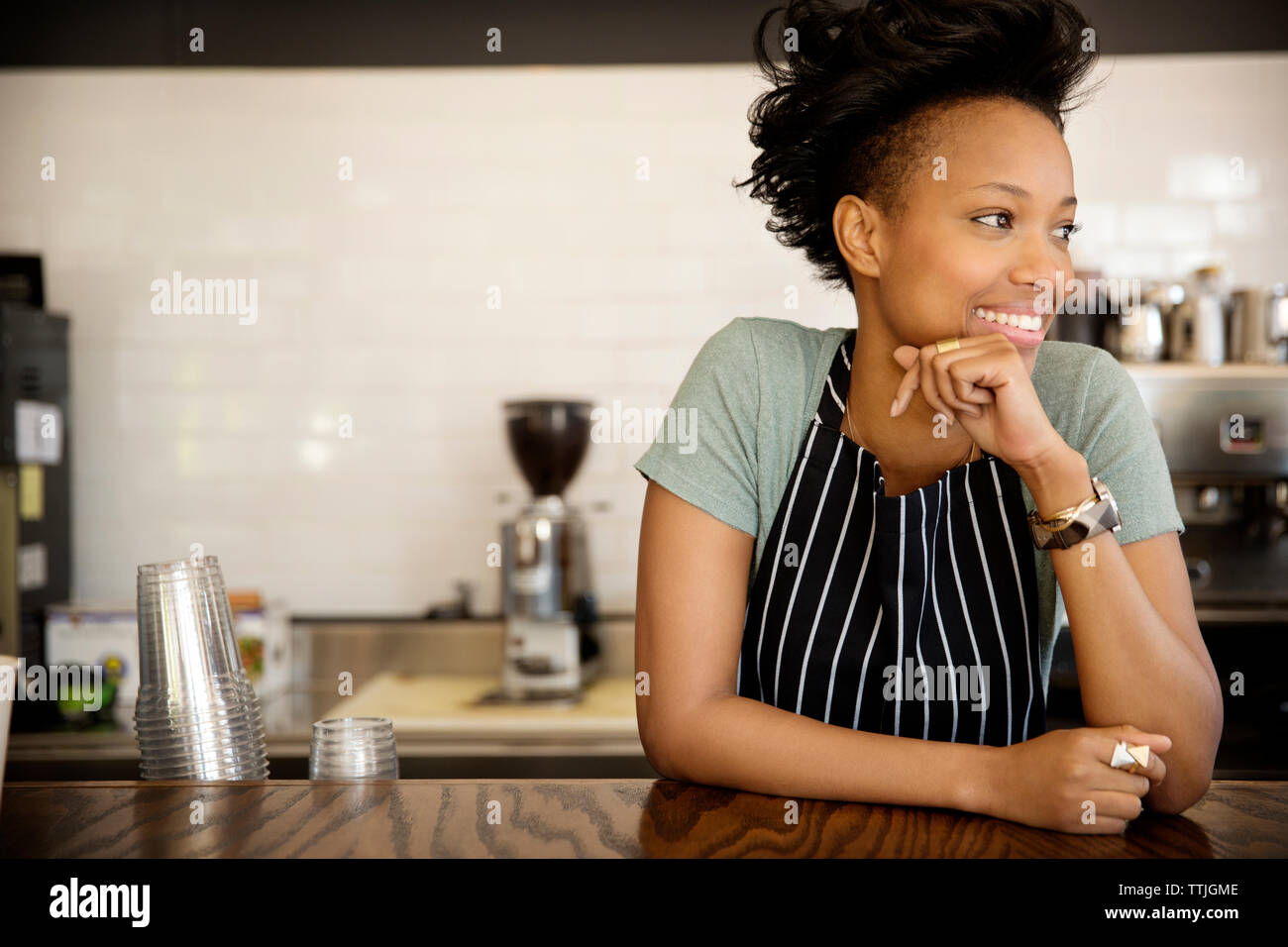 Happy woman looking away while standing at counter in cafe Stock Photo