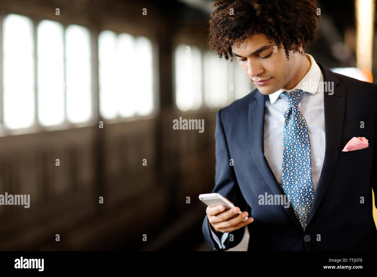 Businessman using phone while standing at station Stock Photo
