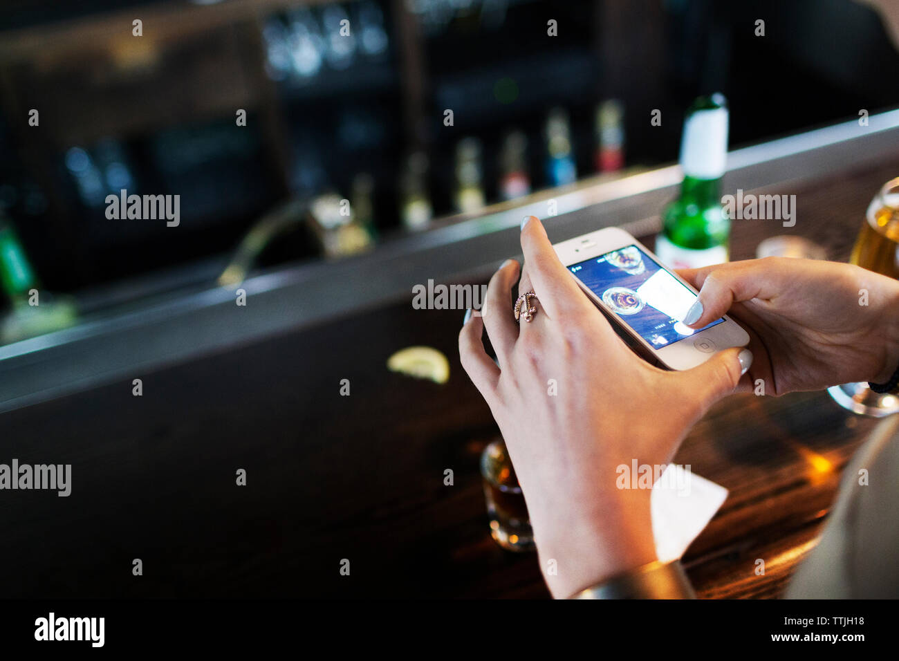 High angle view of woman photographing alcohol on table in bar Stock Photo