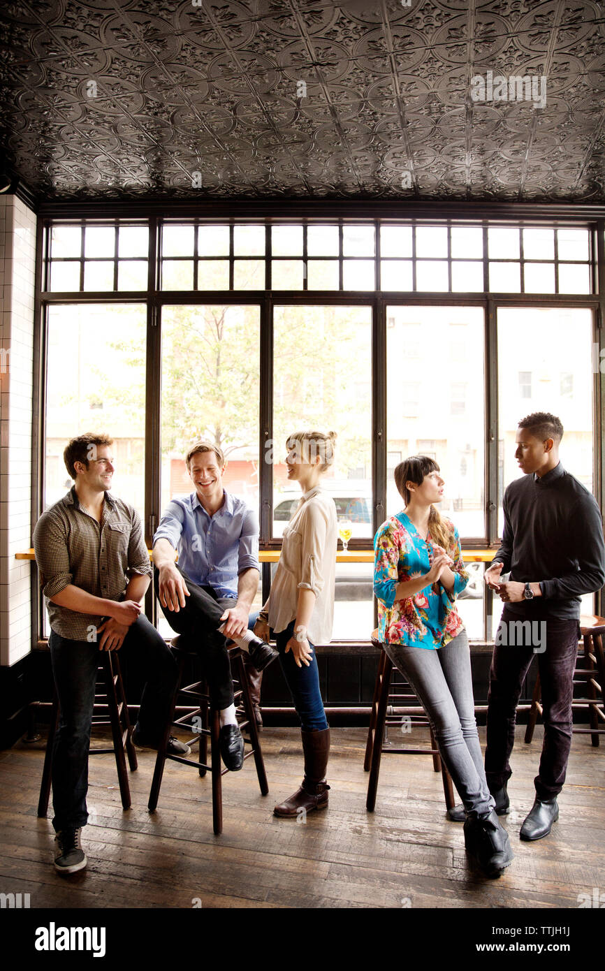 Friends talking while relaxing in bar Stock Photo