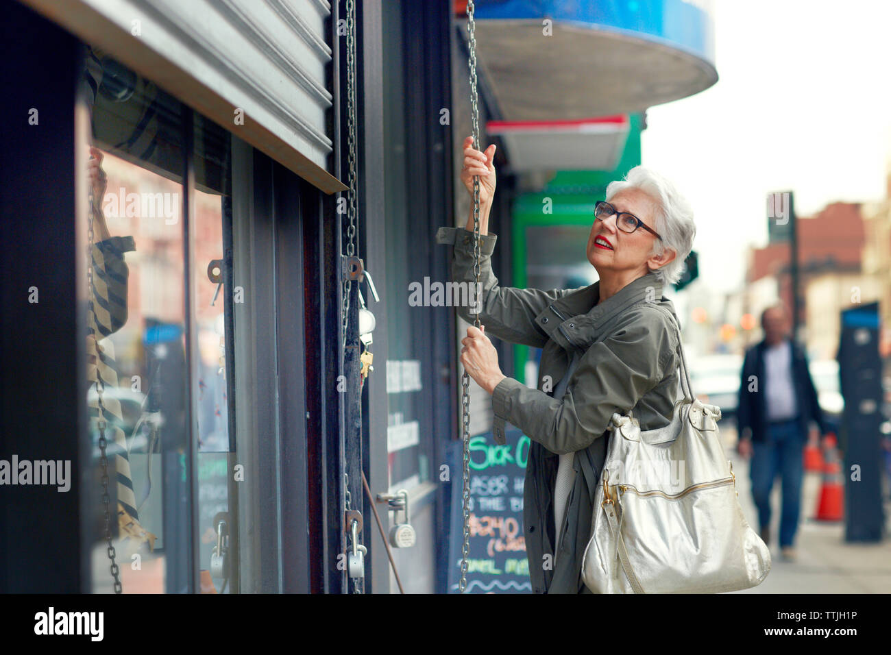 Woman opening store shutter Stock Photo