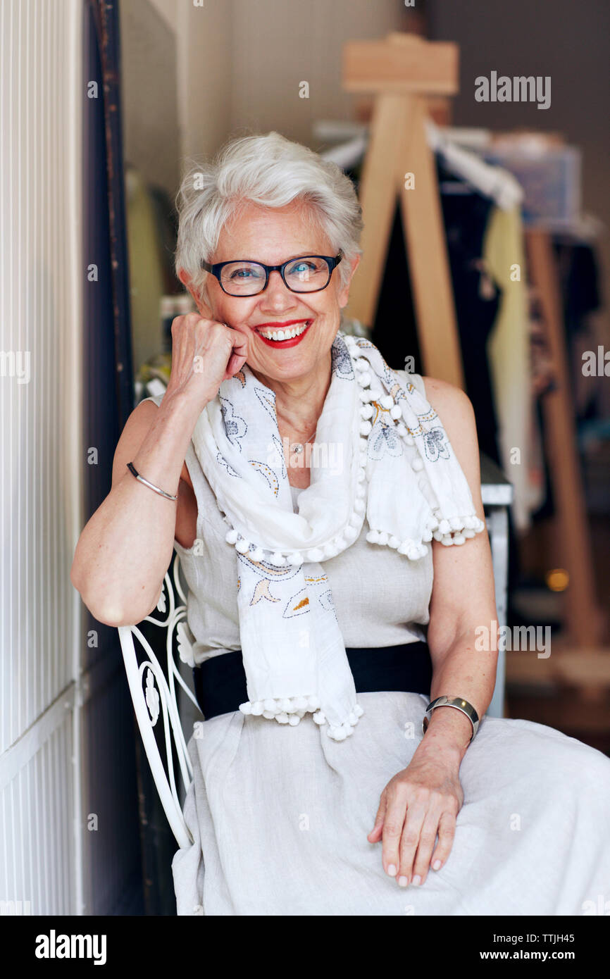 Portrait of senior woman sitting on chair in store Stock Photo