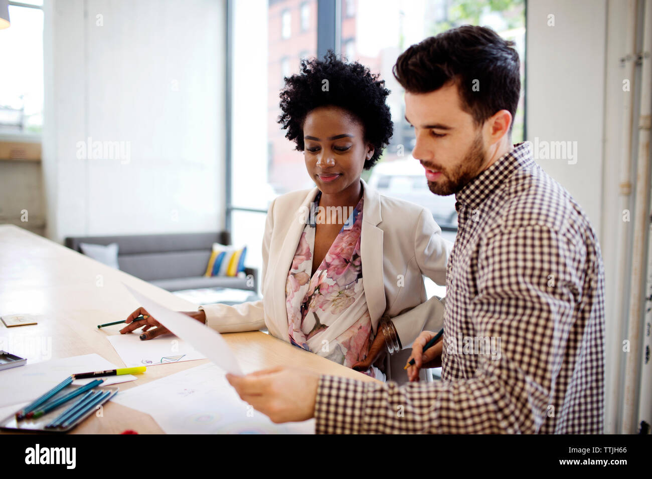 Colleagues discussing document while working in office Stock Photo