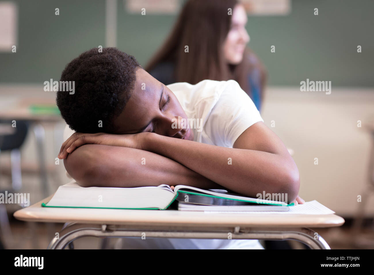 Teenage boy sleeping during lesson in classroom Stock Photo