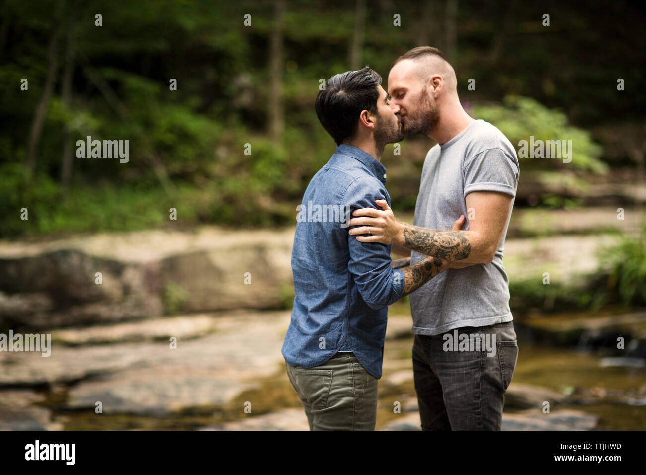 Homosexual couple kissing in forest Stock Photo
