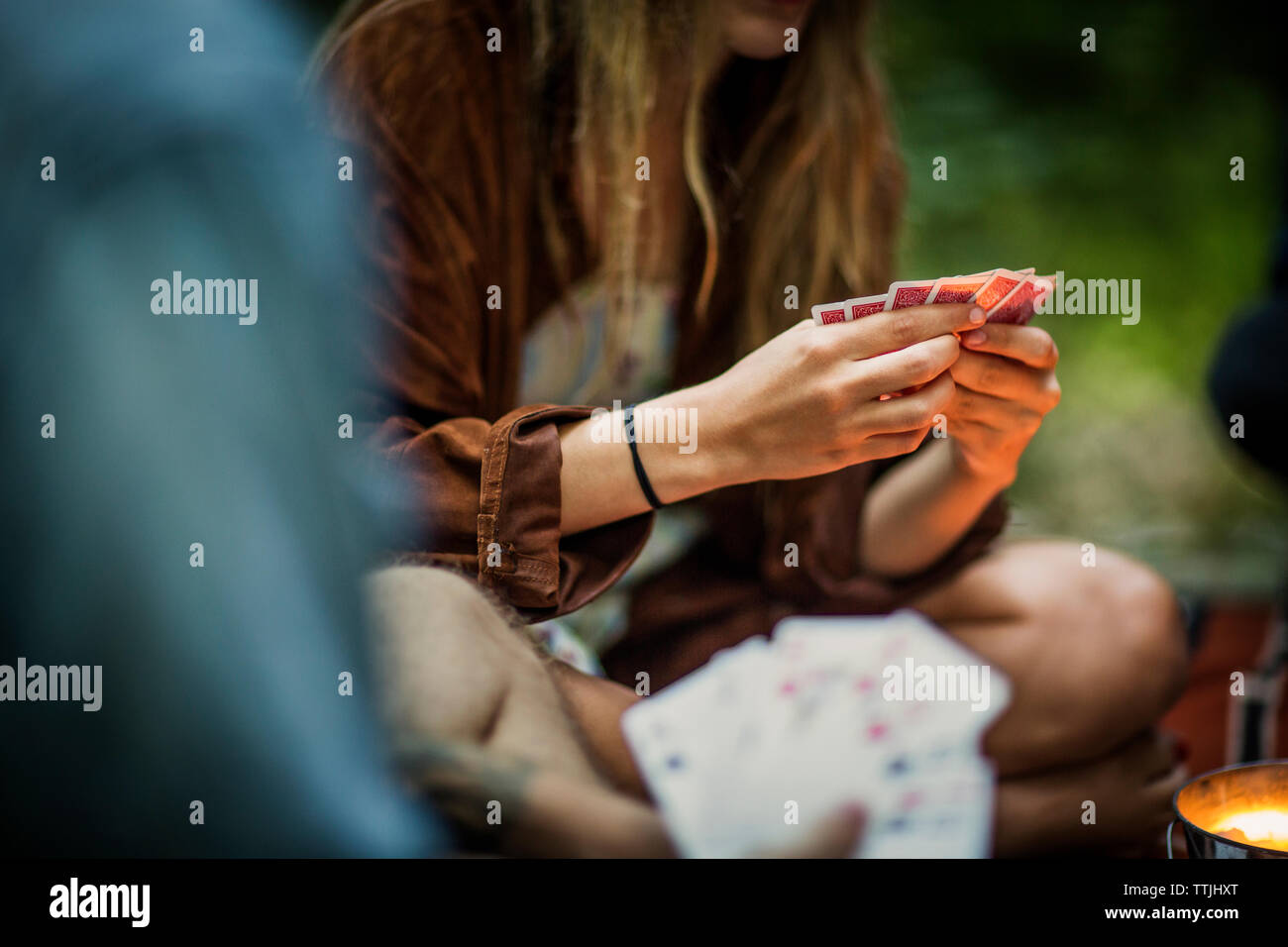 Woman playing card game while sitting on porch in forest Stock Photo