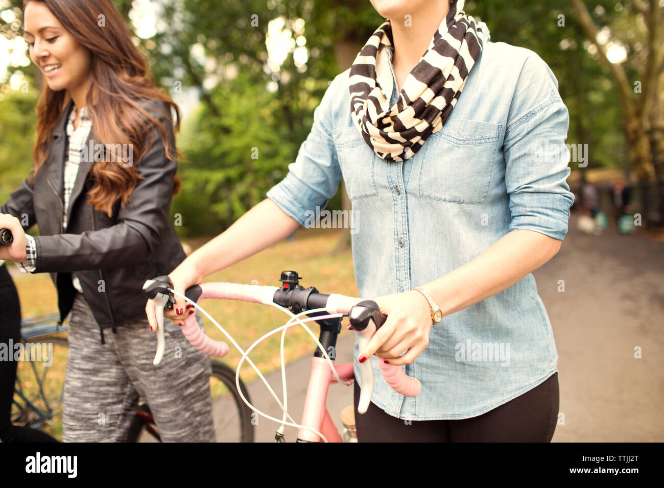 Women with bicycles walking on road Stock Photo