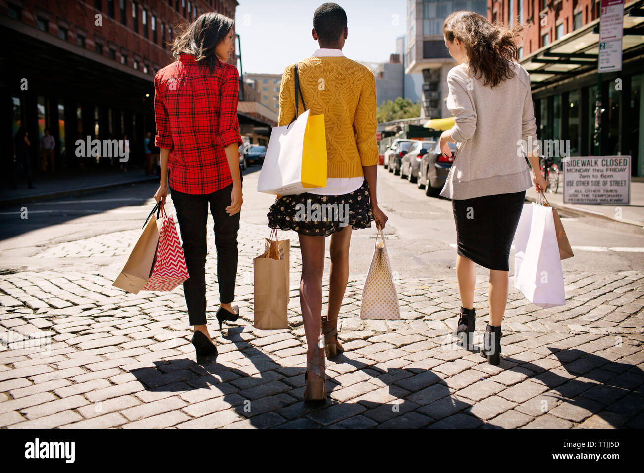 Rear view of women with shopping bags walking on city street Stock Photo
