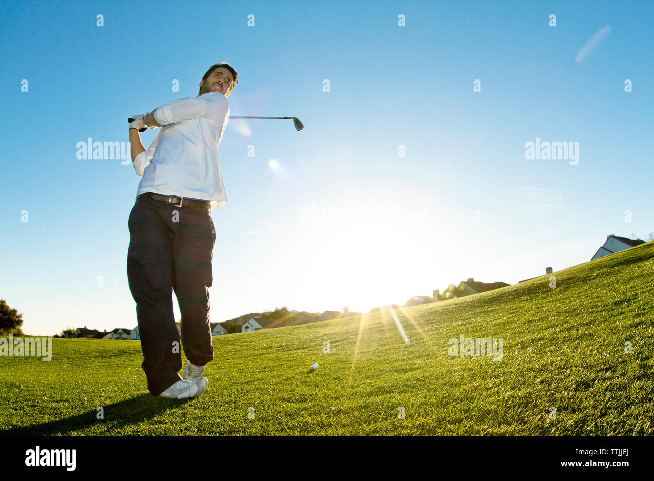 Man taking a shot of golf while standing against clear sky Stock Photo