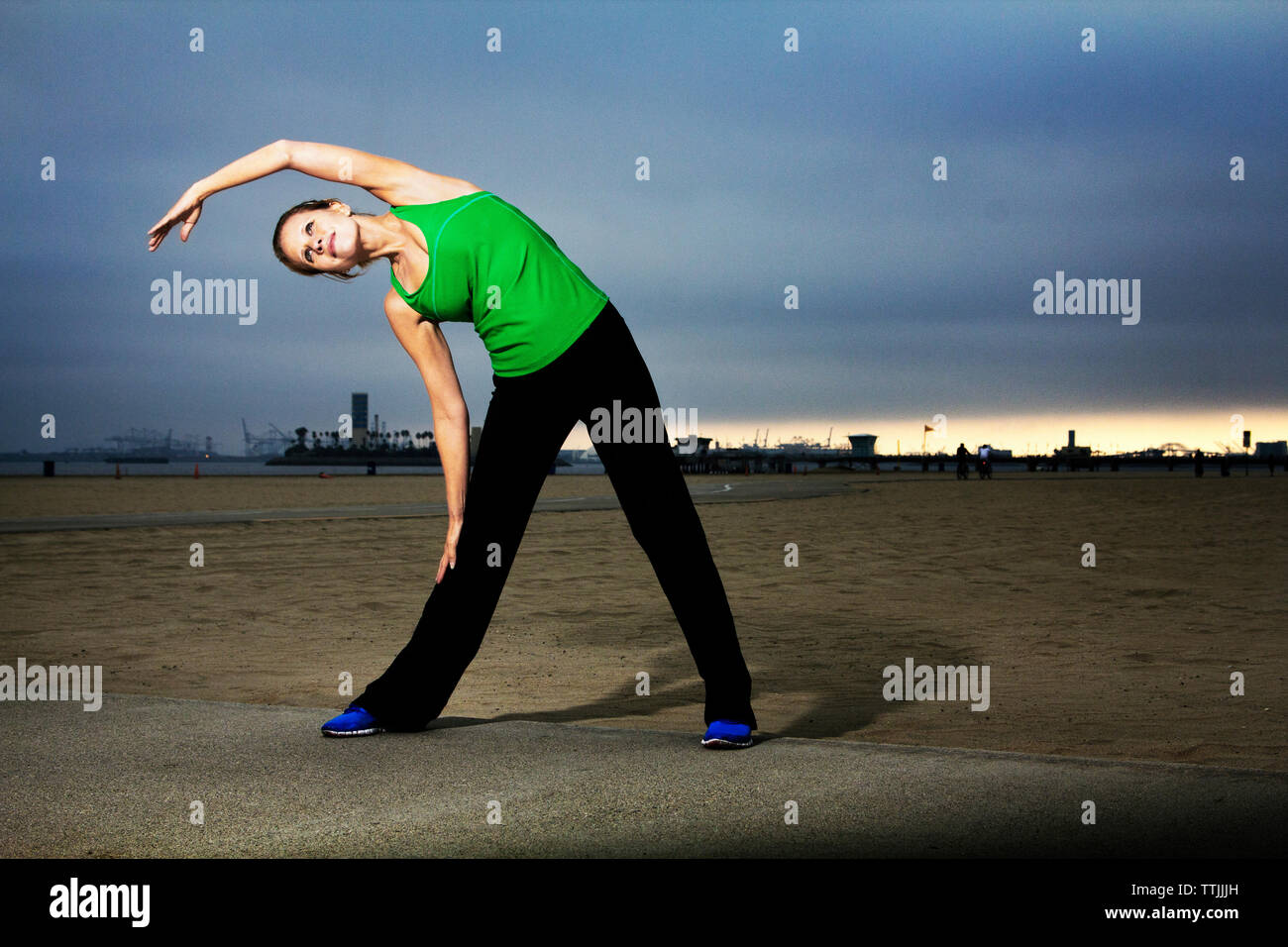 Woman exercising while standing on field at dusk Stock Photo