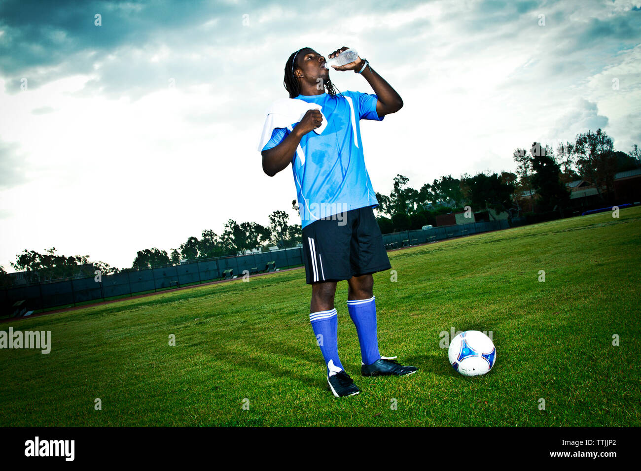 Man drinking water while standing in soccer field Stock Photo
