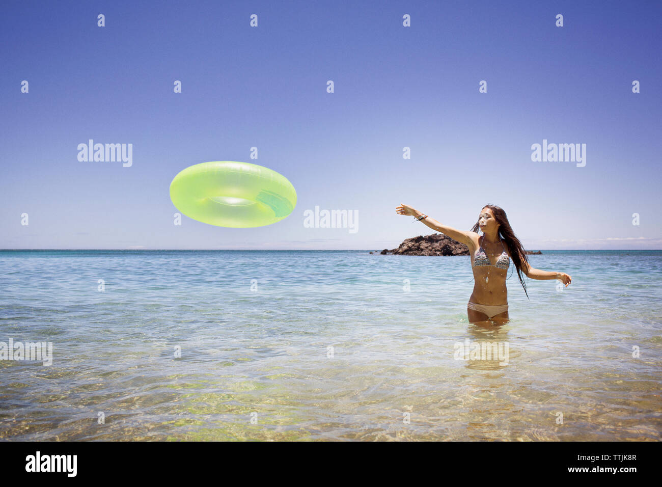 Woman throwing inflatable ring while standing in sea Stock Photo