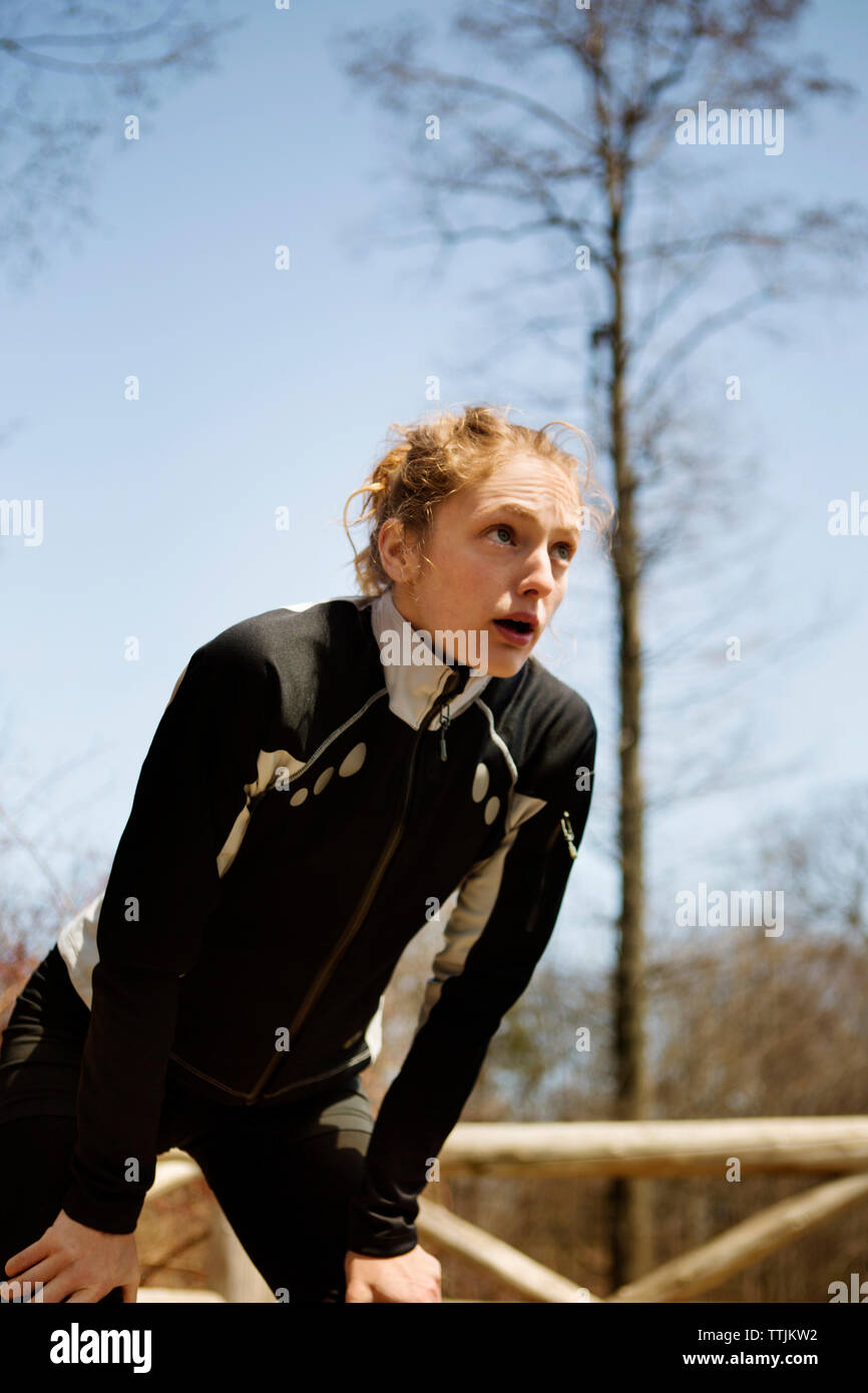 Exhausted woman looking away while standing against sky Stock Photo