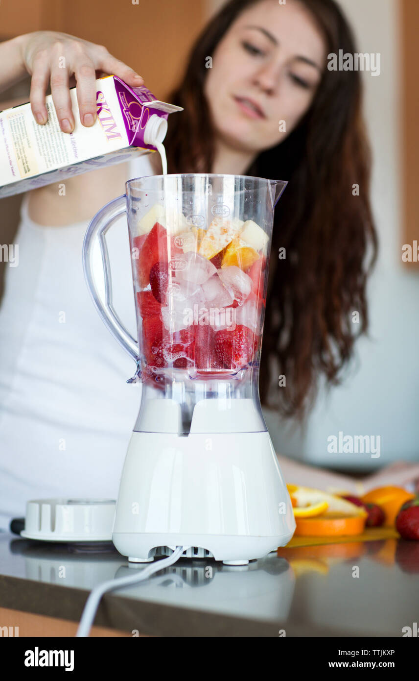 Woman pouring milk in blender while preparing fruit juice at home Stock  Photo - Alamy