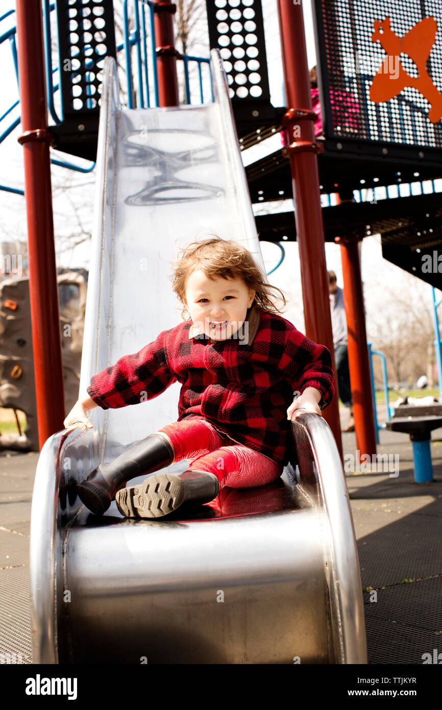Portrait of cute girl sitting on slide at playground Stock Photo - Alamy