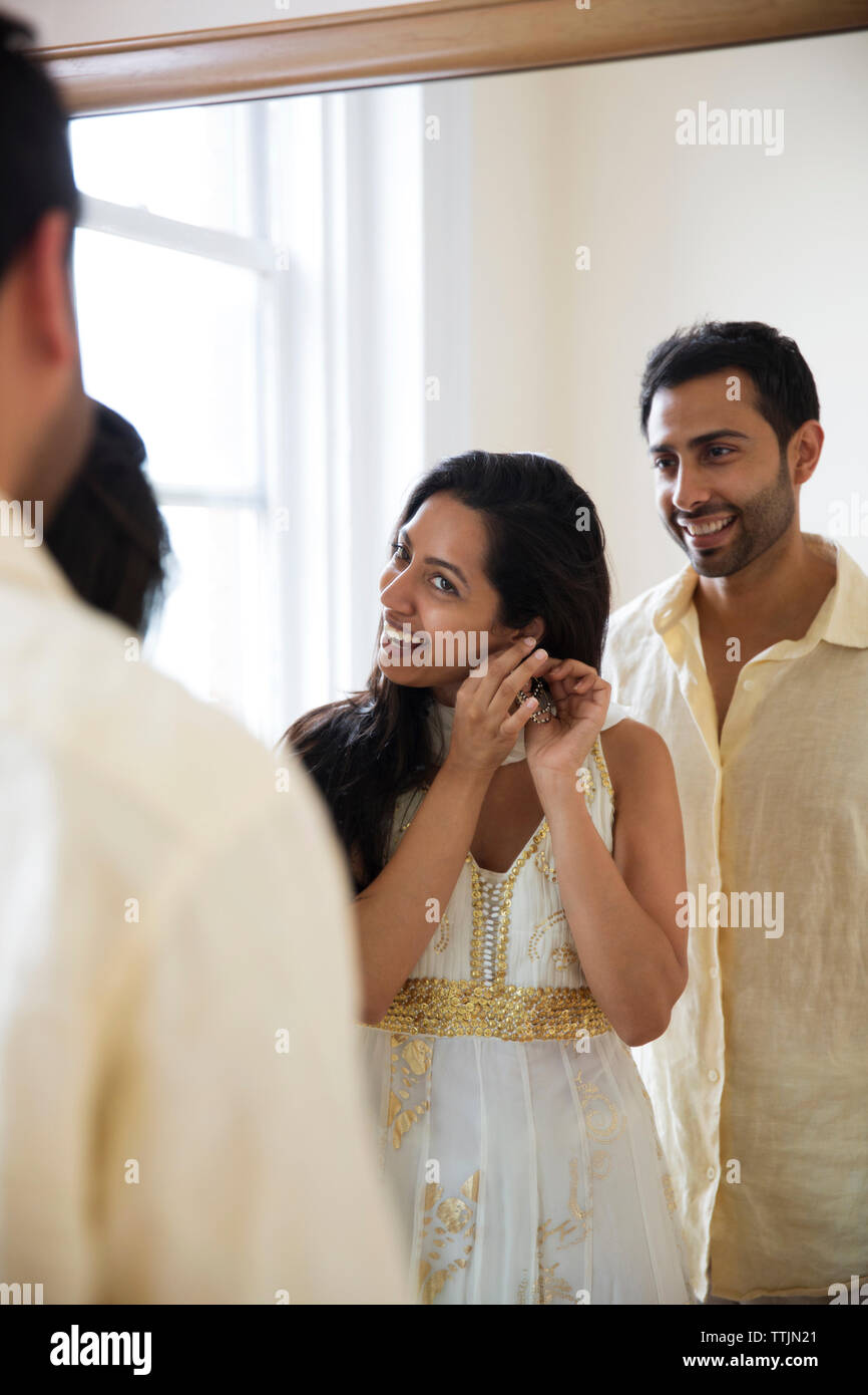 Man looking at woman wearing earring while standing in front of mirror Stock Photo