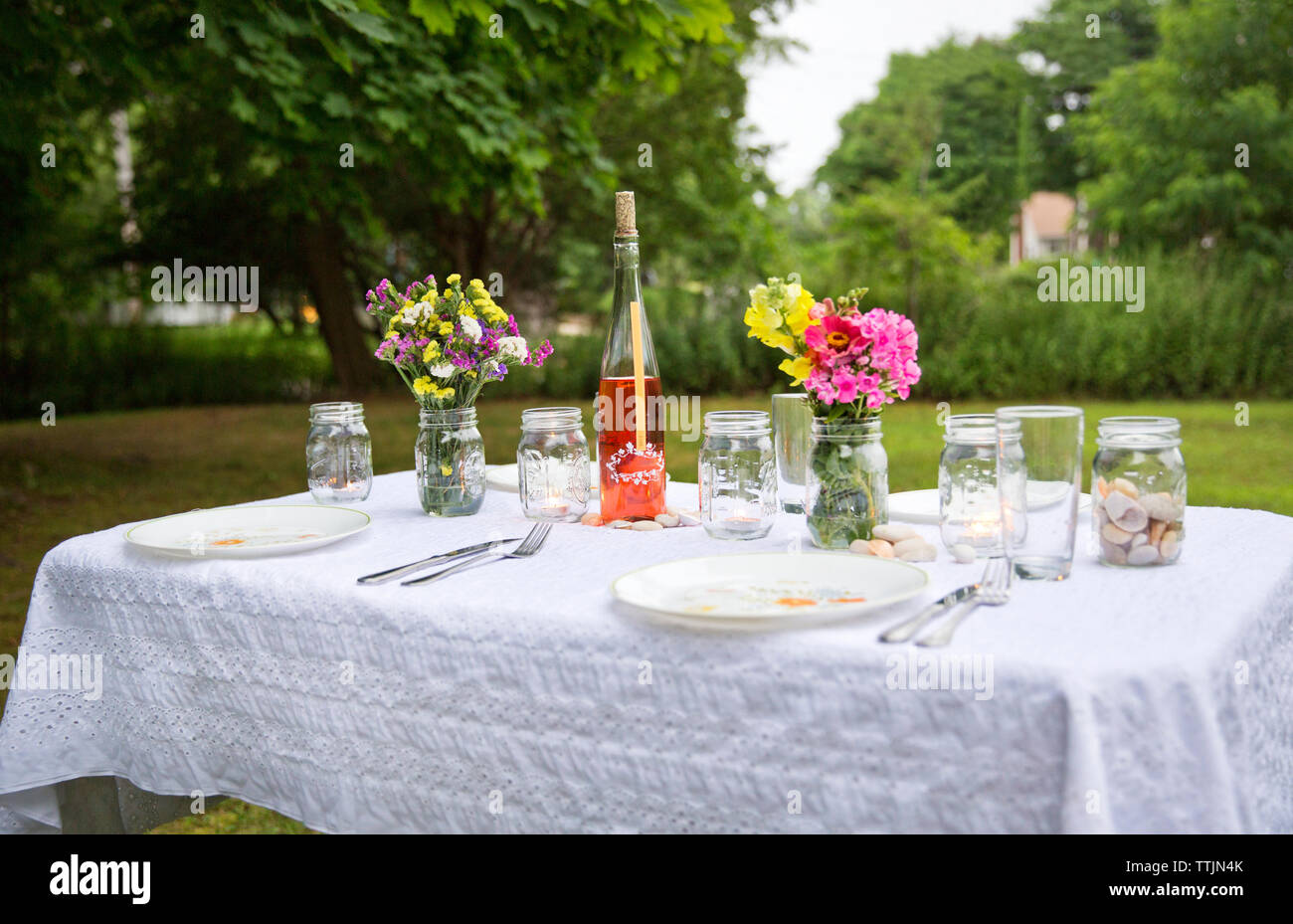 Glass jars and plates on table in backyard Stock Photo Alamy