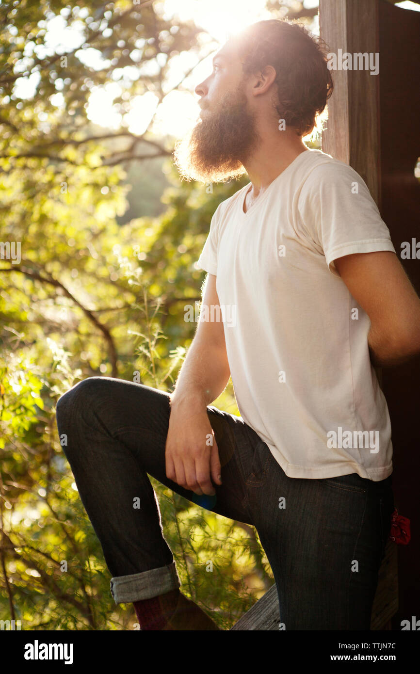 Man looking up while leaning on wooden structure Stock Photo