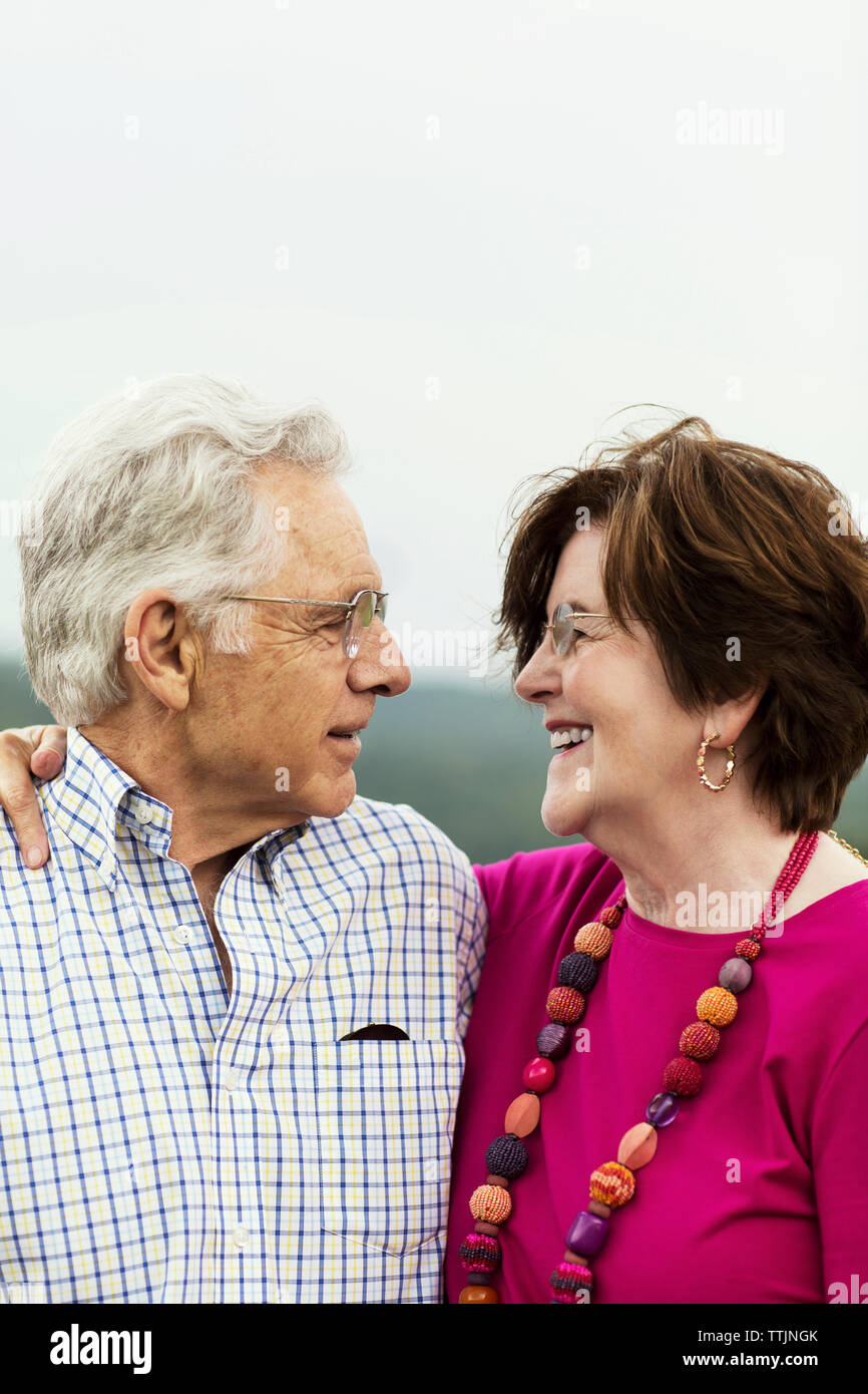 Senior couple with arm around standing against sky Stock Photo