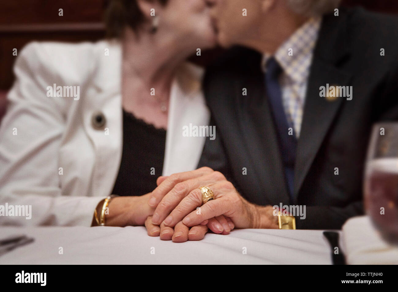 Midsection of senior couple kissing while sitting in restaurant Stock Photo