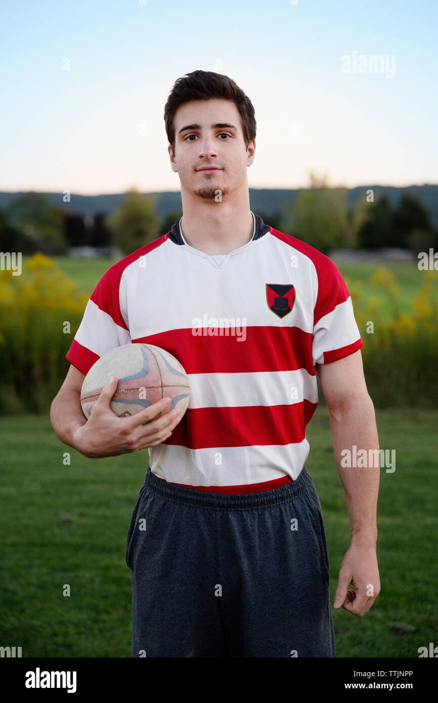 Portrait of player holding rugby ball on field against clear sky Stock Photo