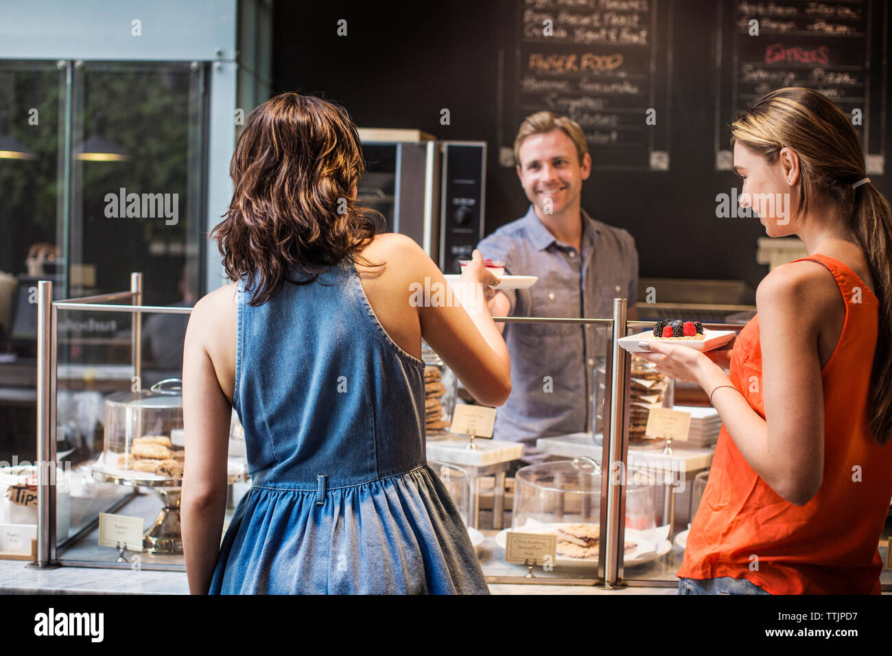 Owner serving dessert to customers at cafe Stock Photo