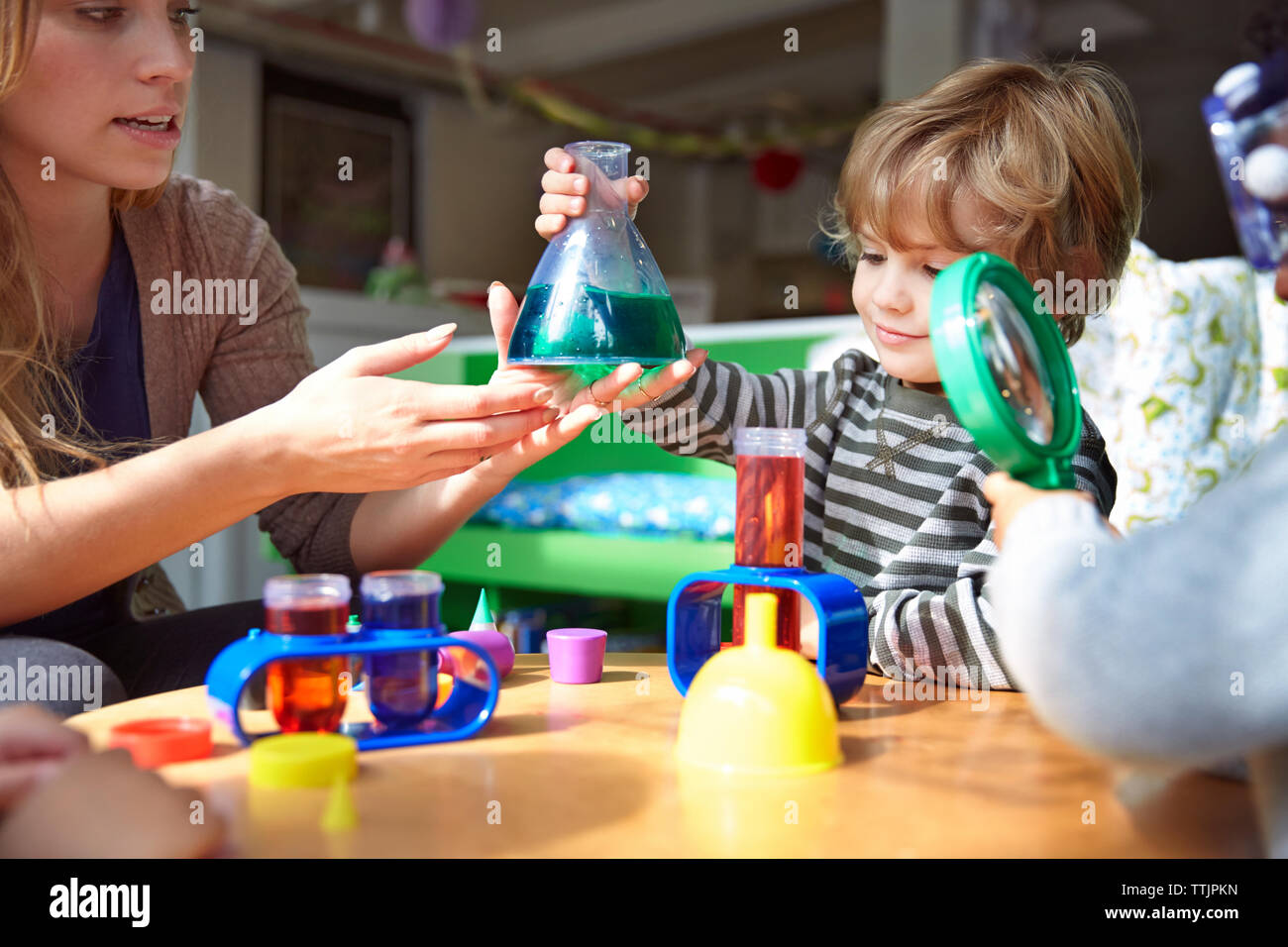 Teacher guiding students in doing science experiment at preschool Stock Photo