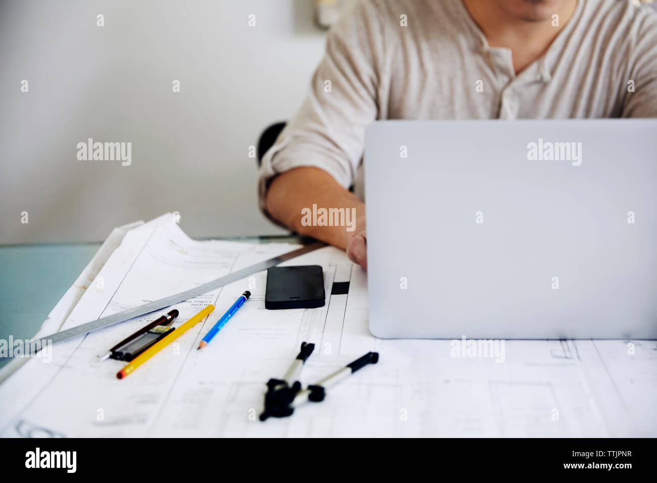 Midsection of man using laptop at table in office Stock Photo