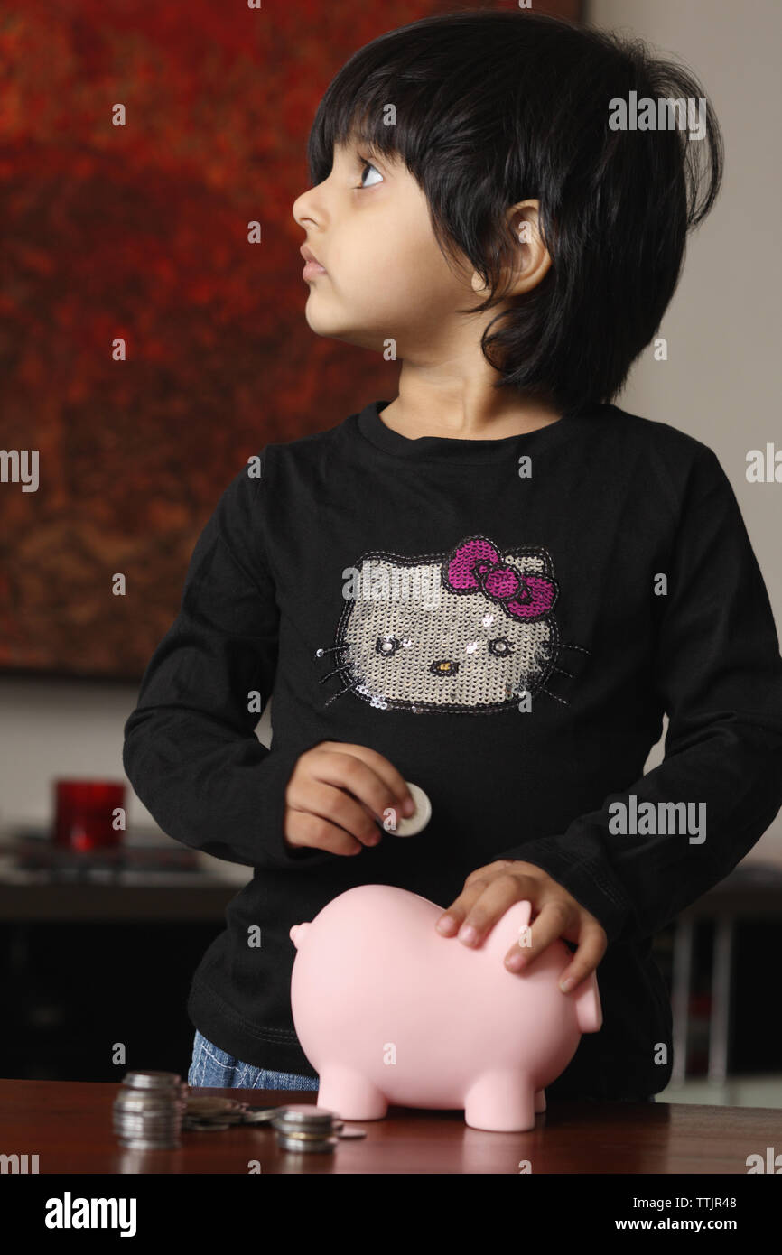 Girl putting a coin into a piggy bank Stock Photo - Alamy