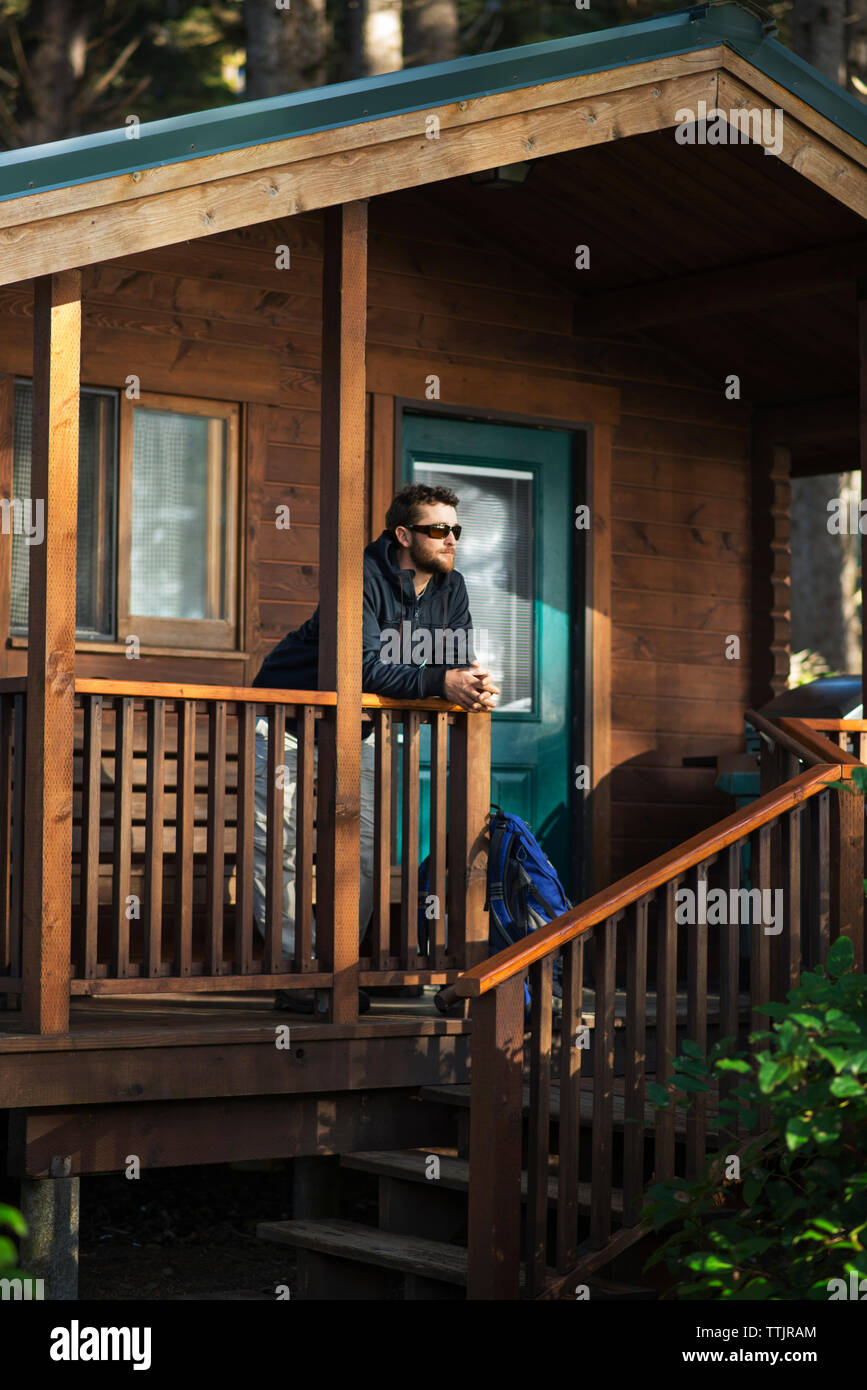 Man looking away while leaning on railing at porch Stock Photo